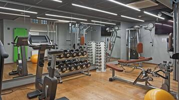 Un gimnasio con equipo de ejercicio, un espejo y una puerta verde.