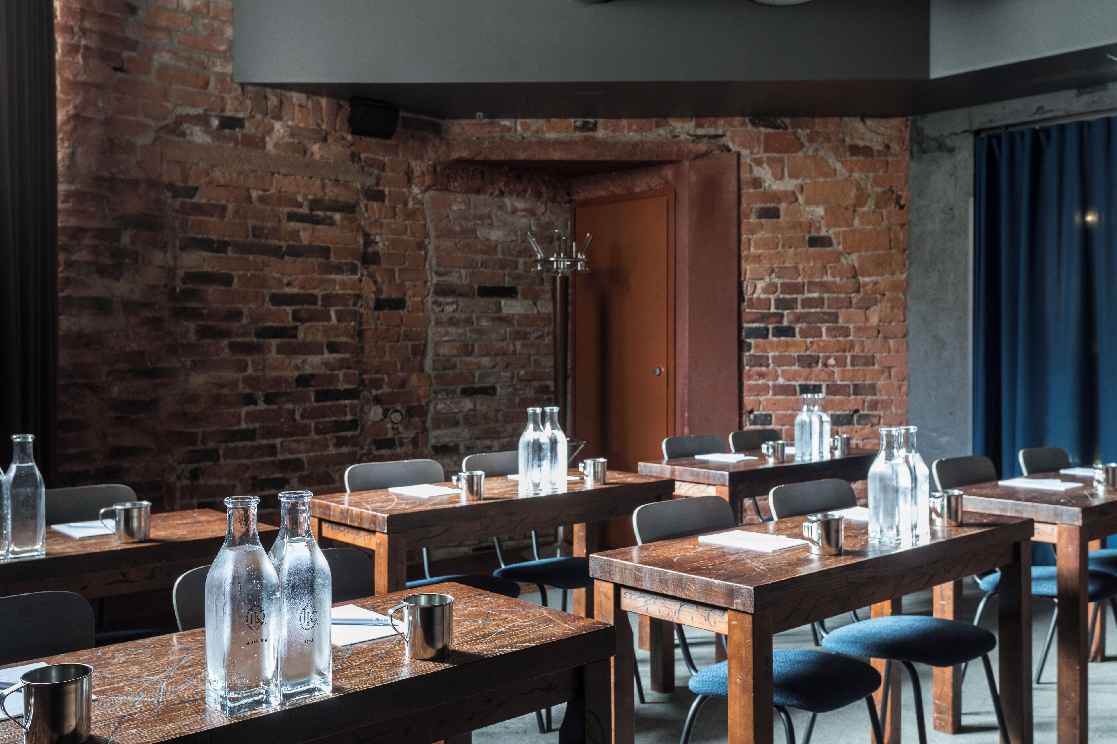 Un restaurant aux murs de briques, aux tables en bois et aux chaises en métal.