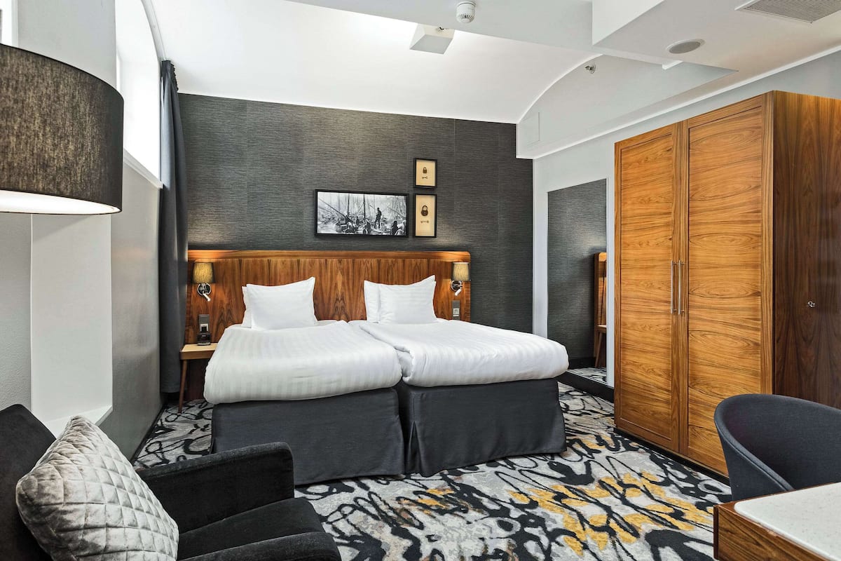 A hotel room with a large bed, a wardrobe, a desk, and a chair.