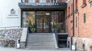 Hotel Katajanokka's indgang med en stenfassade, trapper op til indgangen og et udendørs siddeområde.
