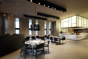 A modern dining area with round tables, black chairs, and a central island with a bar. - Shilla Stay Guro Digital Complex Station (Seoul)