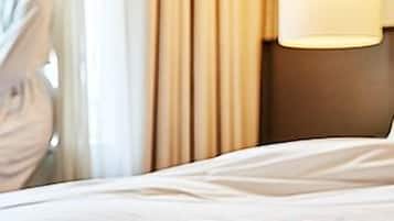 Una habitación de hotel con cama, una taza de café en un atril y una lámpara en la mesita de noche.
