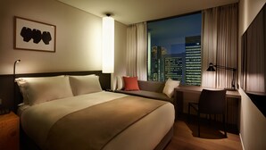 Una habitación de hotel con una cama grande, un escritorio y vistas a la ciudad.