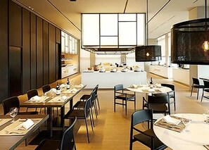 A modern dining area with long tables and chairs, a central island with a kitchen, and a large window providing natural light. - Shilla Stay Guro Digital Complex Station (Seoul)