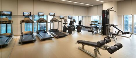A modern gym with treadmills, a bench press, and weight machines.