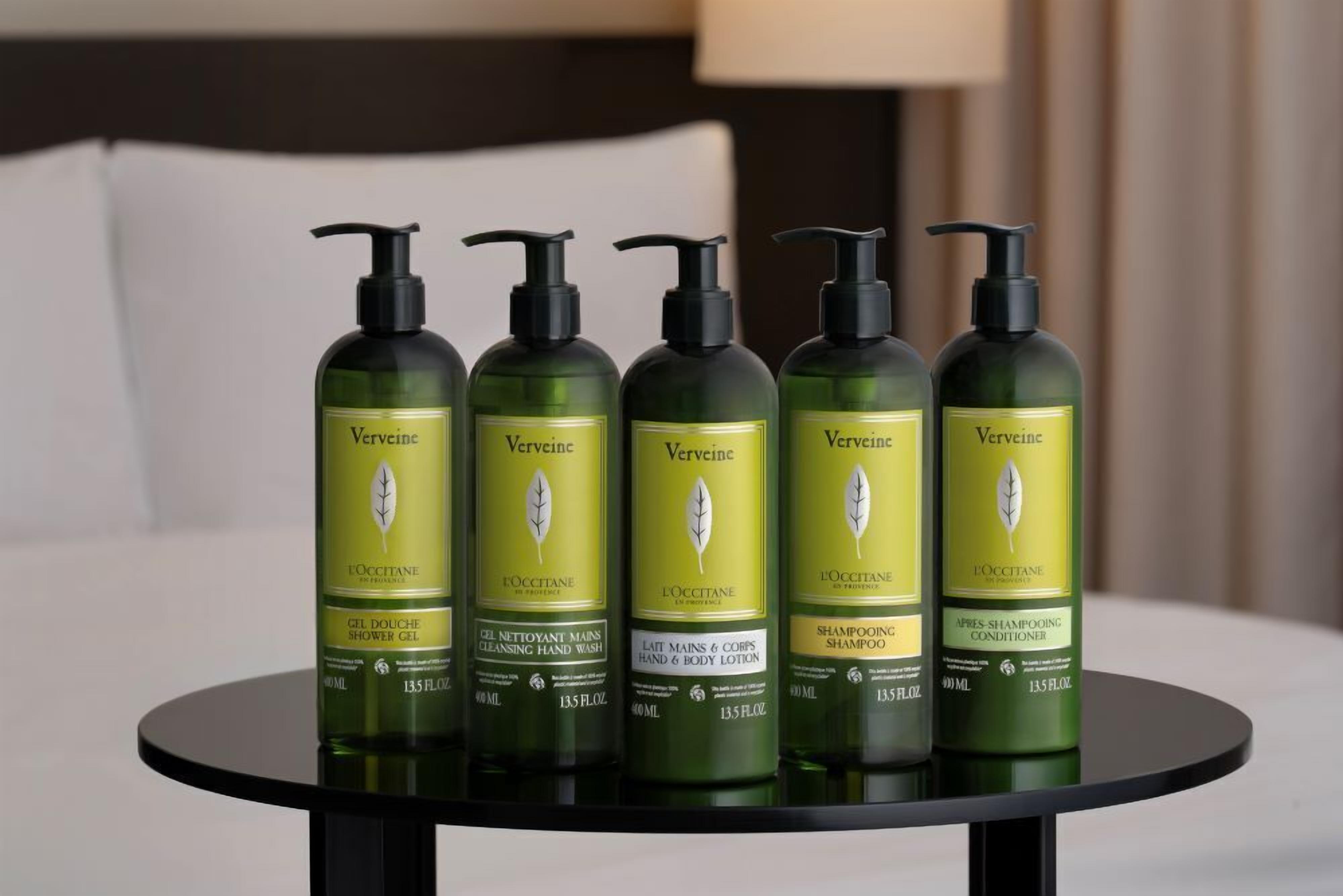 Five bottles of Vervine L'OCCITANE products on a round table.
