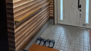 Een kamer met houten lambrisering, een deur met een greep en een betegelde vloer.