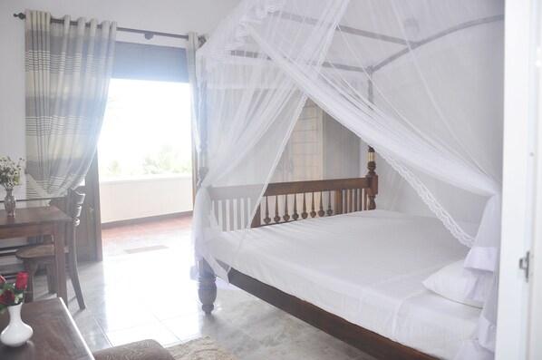 A bedroom with a wooden bed, white bedding, and a canopy. - Supunvilla (Bentota)