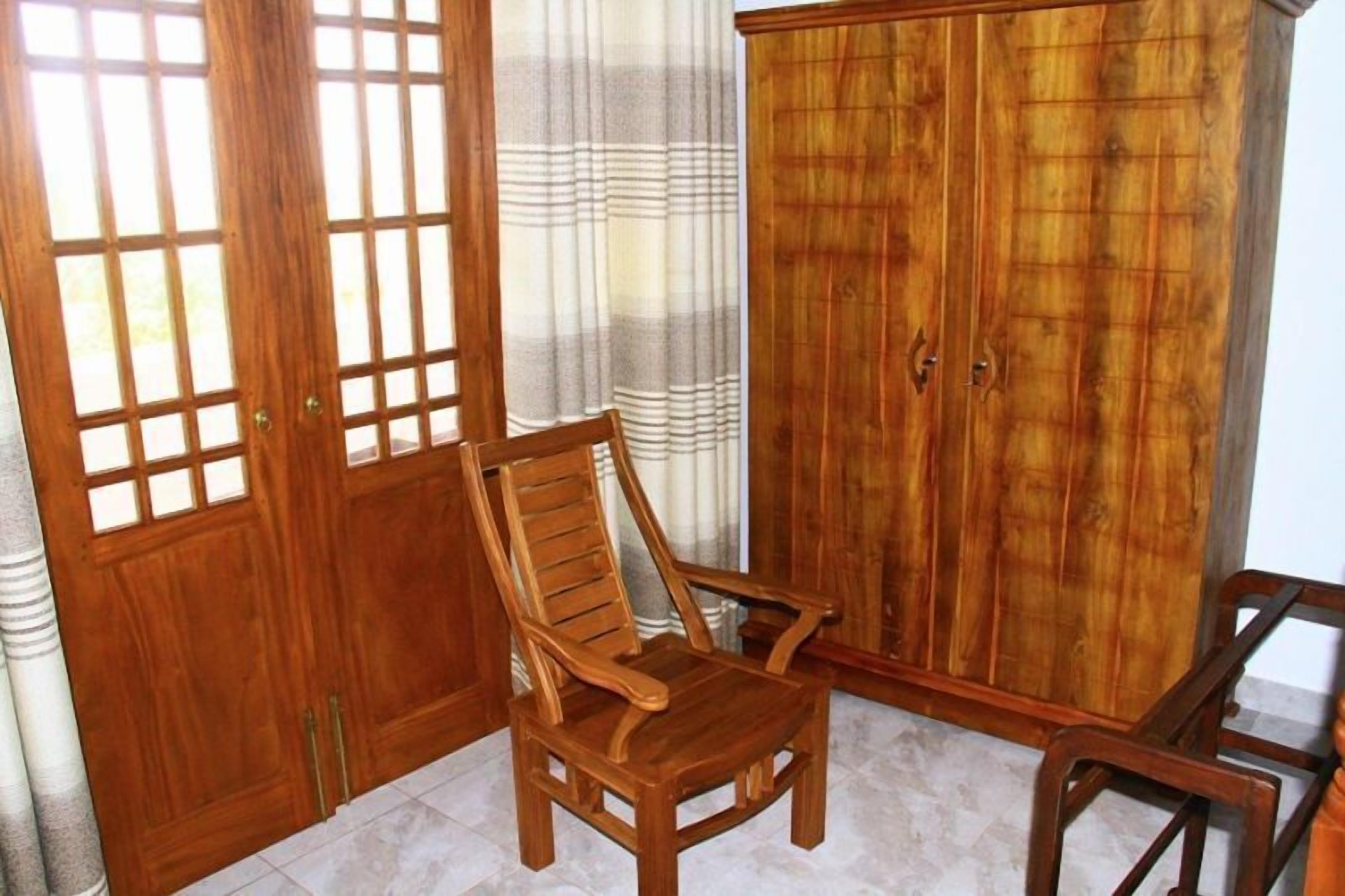 A wooden chair in a room with a wardrobe and a curtain.