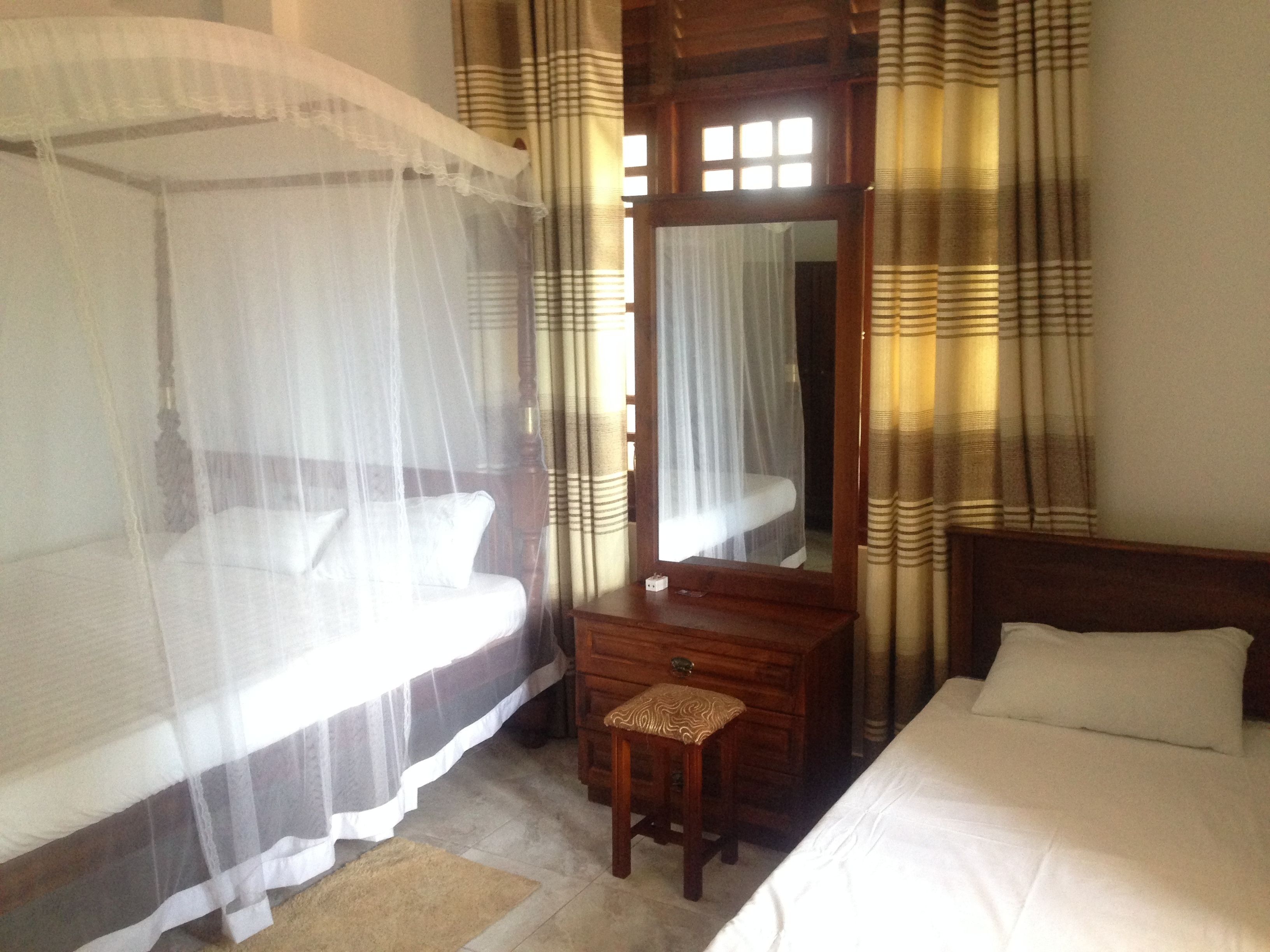A bedroom with two single beds, a wooden dresser, and a mirror.