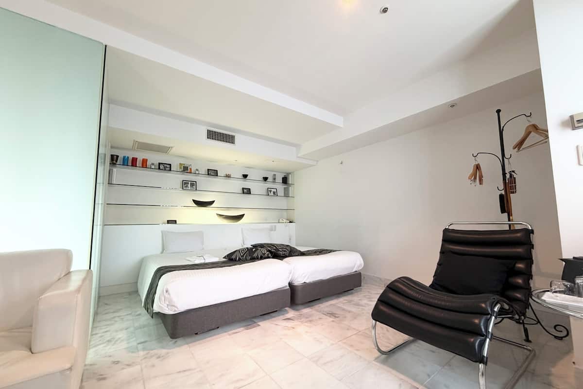 Een moderne slaapkamer met een bed, een stoel en een plank met spullen.