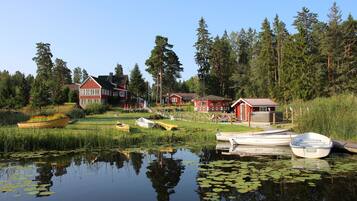 Järvenrantatontti, jossa on laiturissa kiinni useita veneitä, puinen vene, jossa on kukkia, ja punainen rakennus.