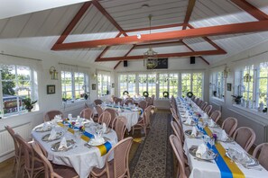 A long dining table set for a formal event with white tablecloths, silverware, and floral centerpieces. - Odalgården (Uppsala)