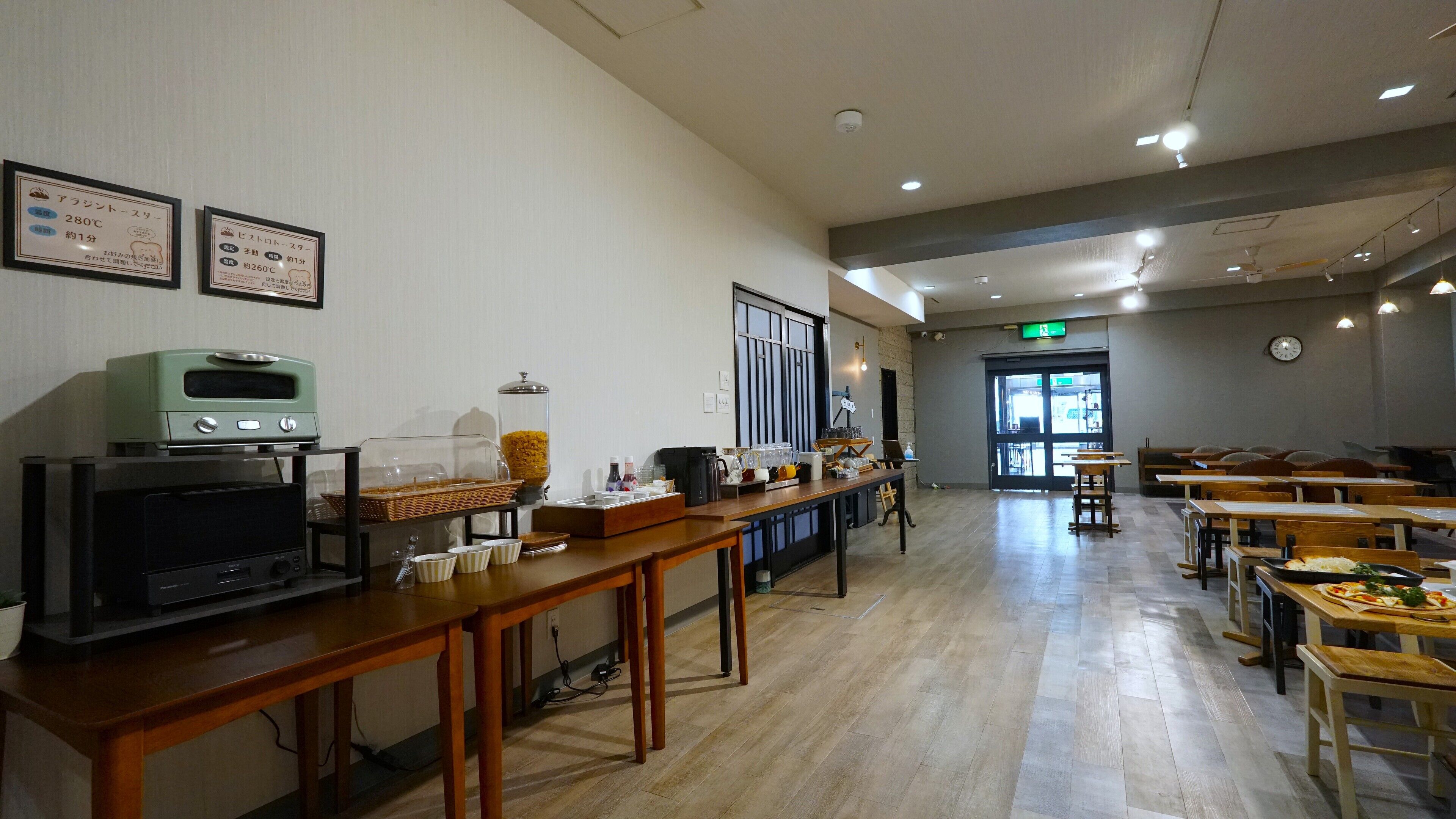 A cafeteria with wooden tables and chairs, a buffet area with food and drinks, and a clock on the wall.