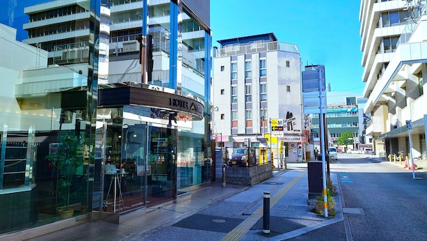 Un hotel moderno con fachada de vidrio, situado en una calle de la ciudad junto a otros edificios.