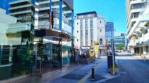 A modern hotel with a glass facade, located on a city street with other buildings. - Hotel AreaOne Oita (Oita)