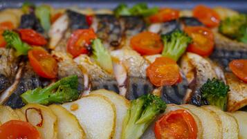 Primer plano de pescado a la parrilla con verduras.