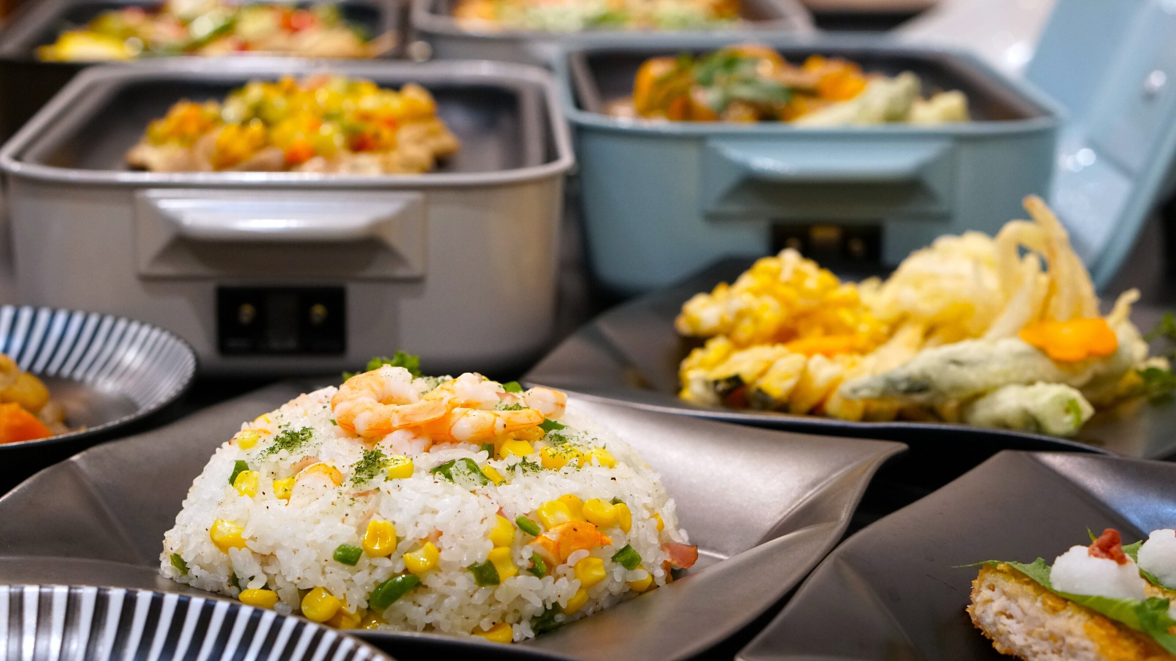 A buffet with various dishes including rice with corn and shrimp, and other prepared foods.