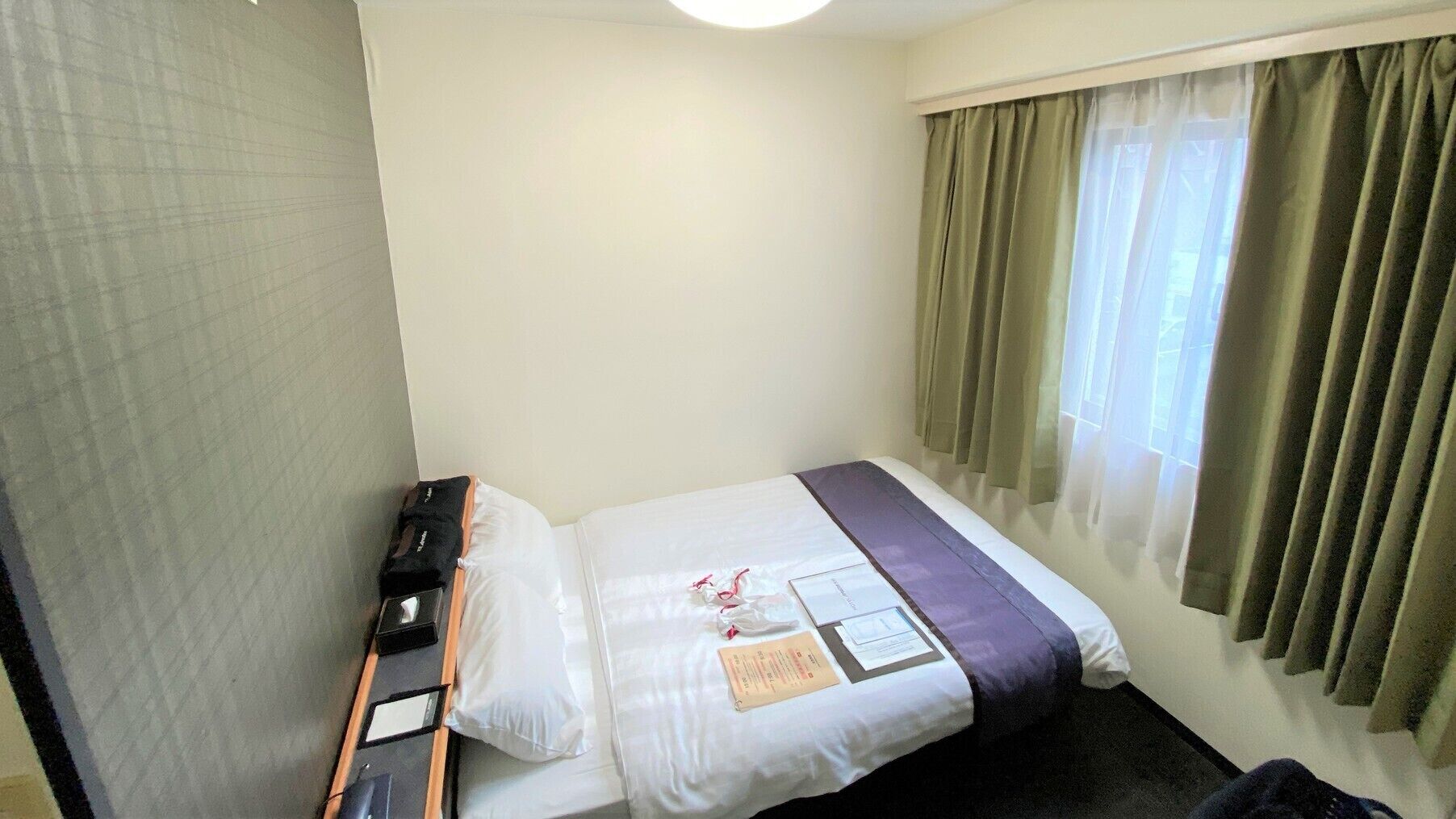 A hotel room with a bed, a desk, a chair, and a window with curtains.