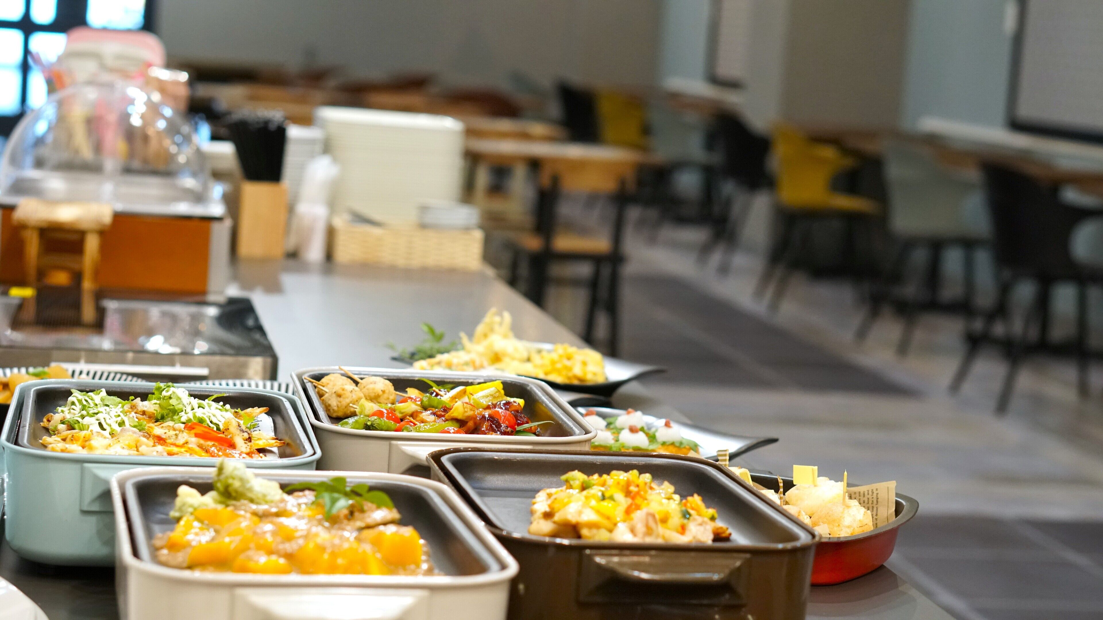 A buffet with various dishes in trays, including salads, meats, and desserts.