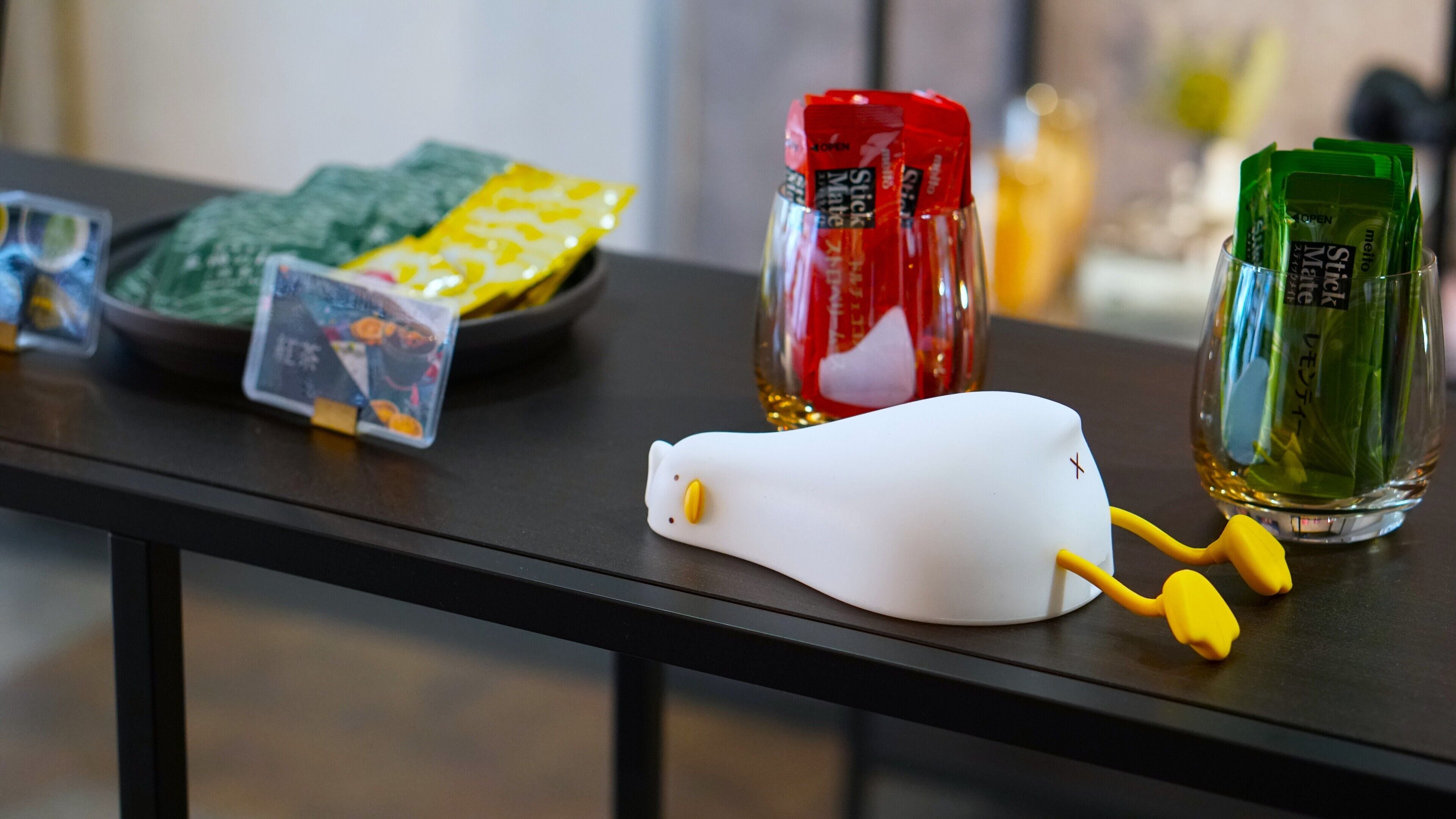 A table with various items including a white object, a red bottle, and green packets.