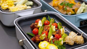 A buffet with skewers of meat, vegetables, and corn.