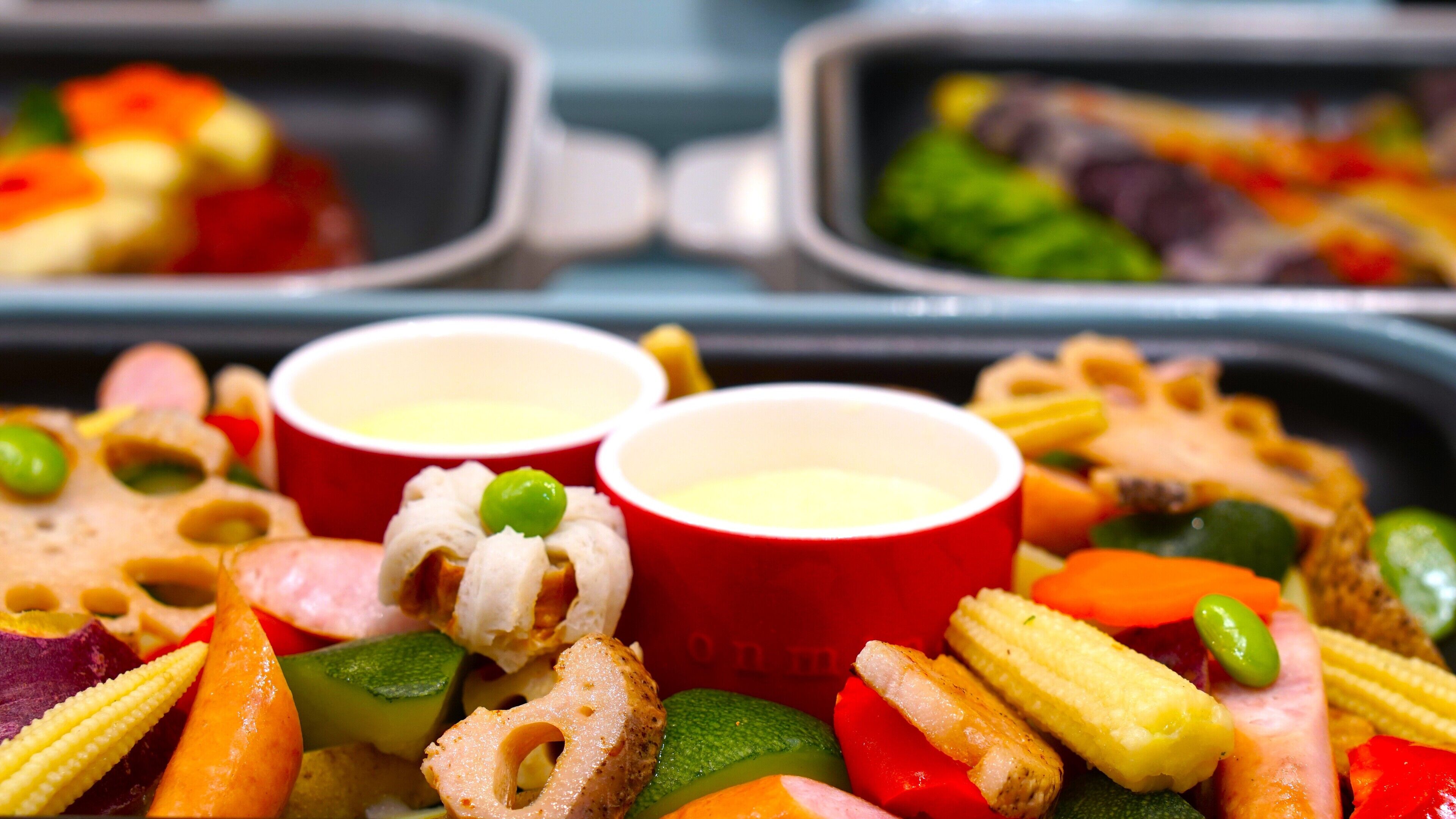 Una bandeja con diversos bocadillos y dos vasos rojos, probablemente con bebidas, dispuesta sobre una mesa.