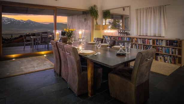 A dining area with a large table, chairs, and a view of mountains.