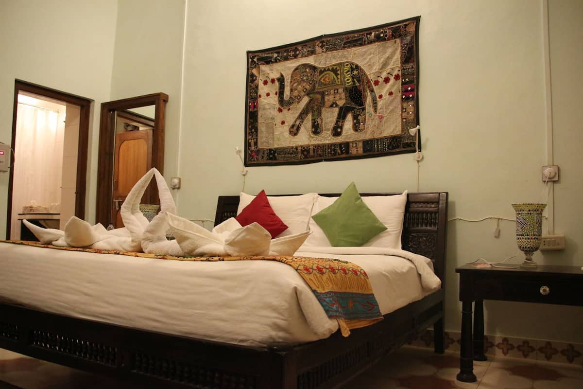 Una cama bien hecha con toallas, almohadas y un tapiz decorativo con un elefante.