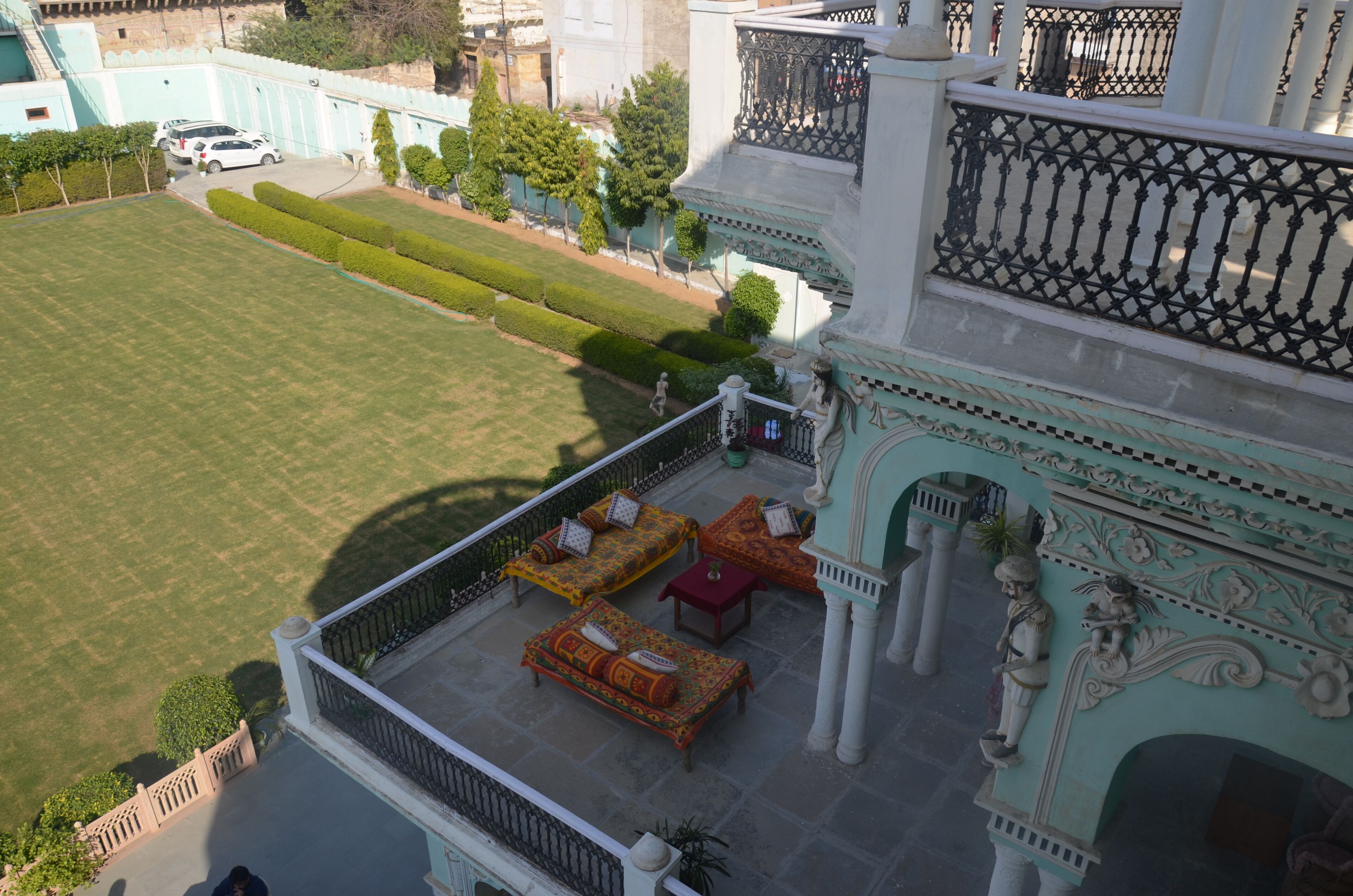 A rooftop terrace with a lawn, seating area, and decorative columns.
