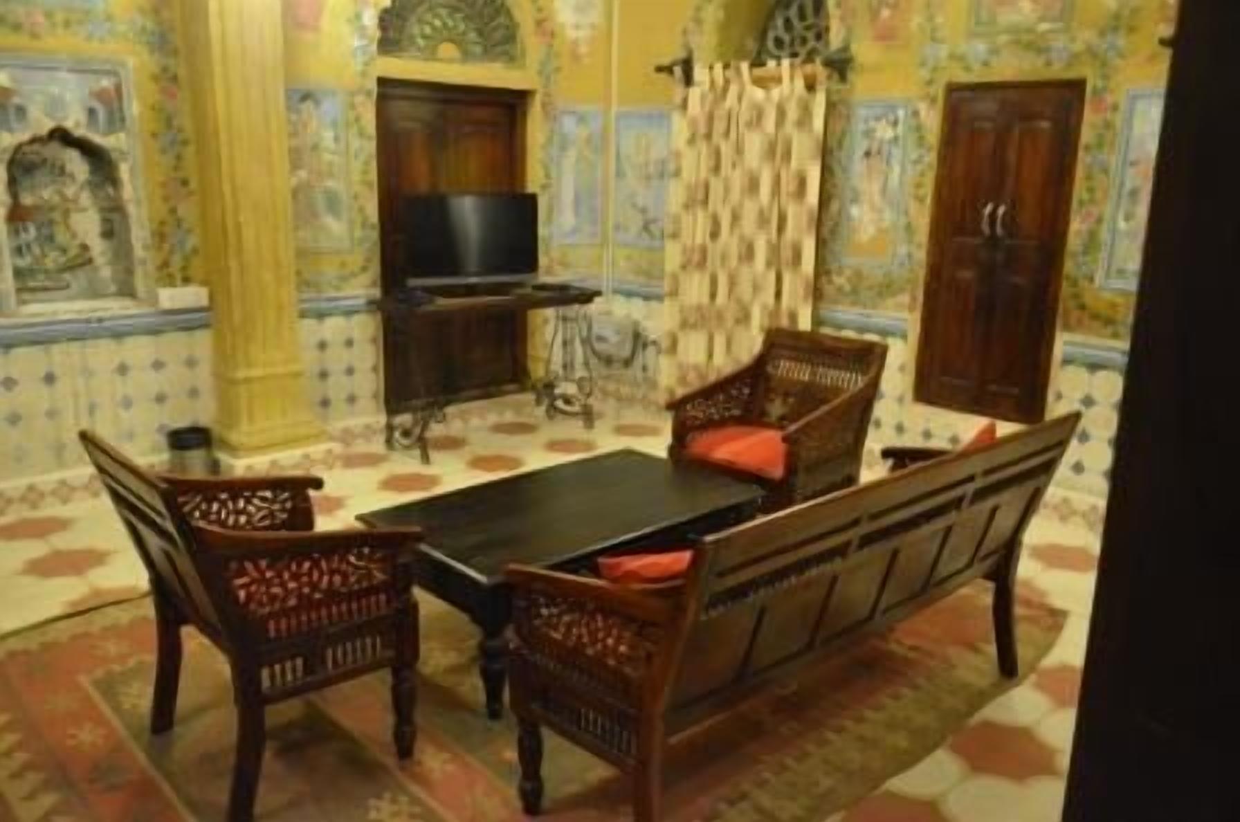 A traditional room with a sofa set, a television, and patterned walls.