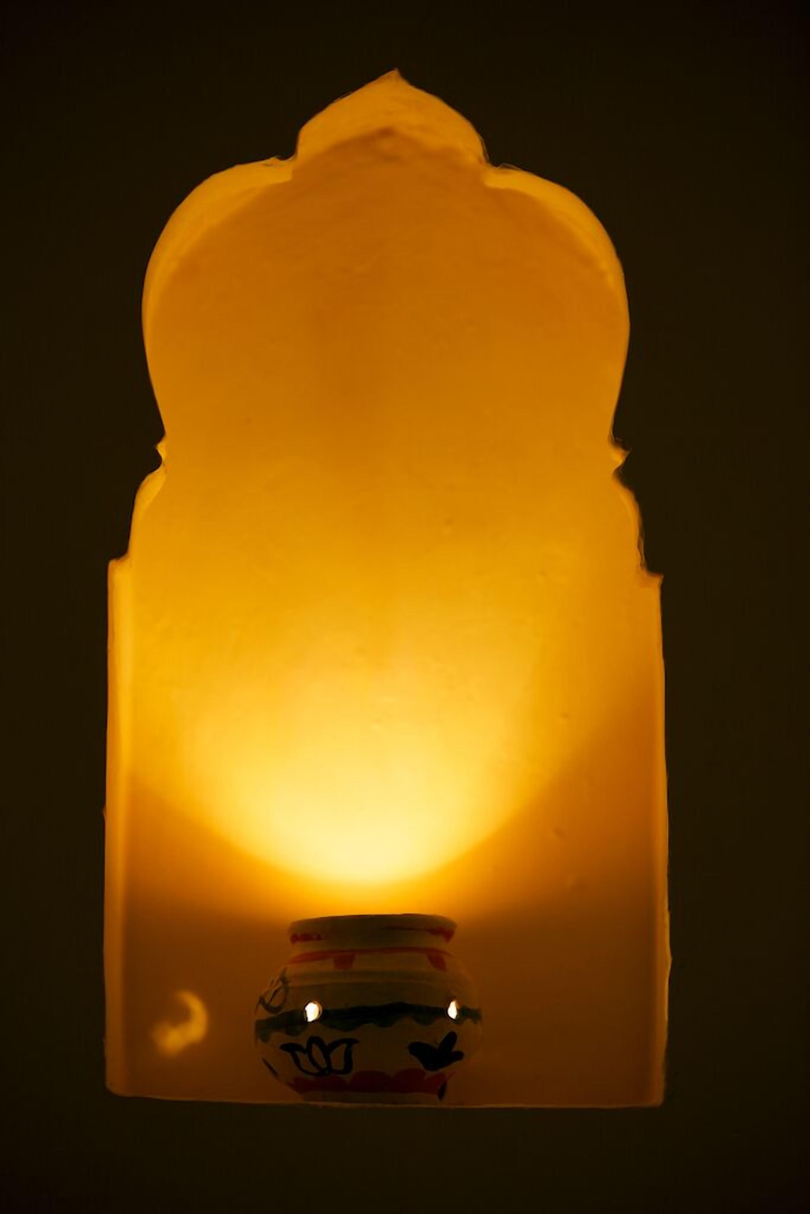 A candle with a decorative holder, casting a warm glow.