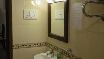 A bathroom with a sink, mirror, towel rack, and a wall-mounted light switch.