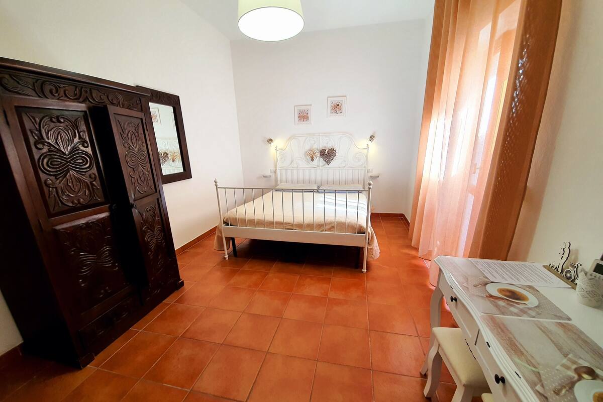 A bedroom with a bed, a dresser, a table, and a chair.