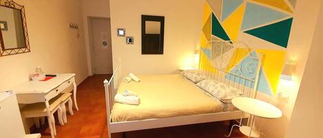 A bedroom with a bed, bedside table, and a desk with a chair.