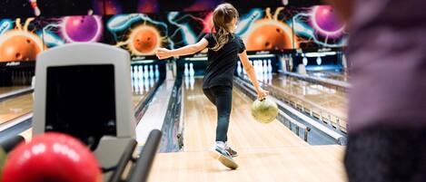 Pista de boliche com alvos, pinos e bola em movimento.