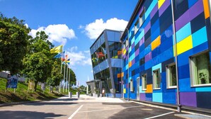 Un bâtiment moderne à la façade colorée, doté de grandes fenêtres et surplombant un ciel dégagé.