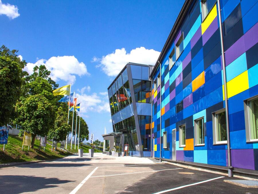A modern building with a colorful facade, large windows, and a clear sky.