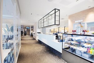 Un vestíbulo de hotel con una recepción, una vitrina con alimentos y una alfombra estampada.