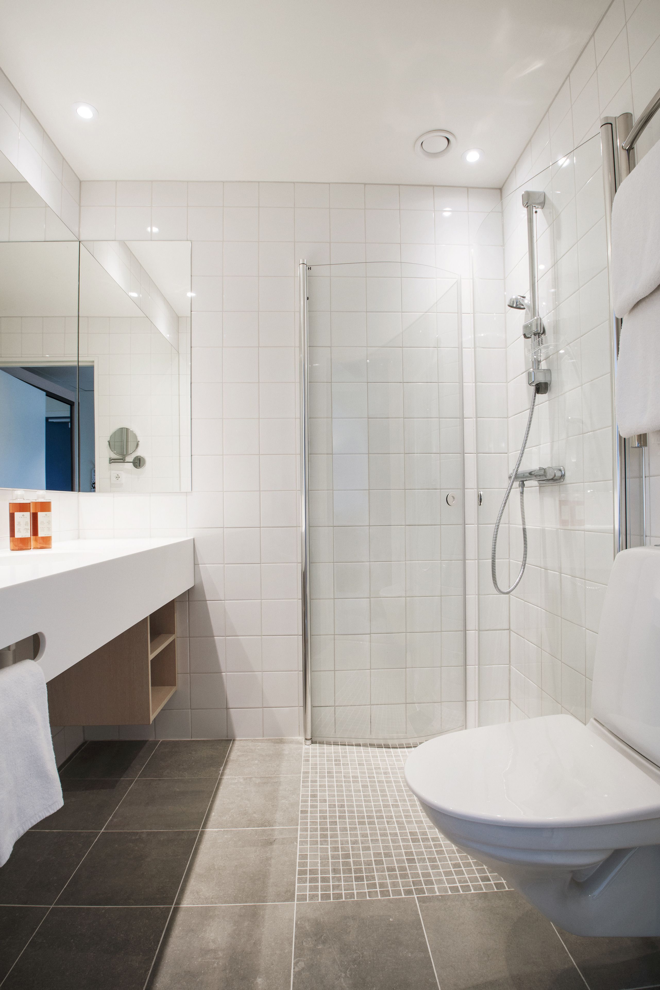 A modern bathroom with a shower, toilet, and vanity.