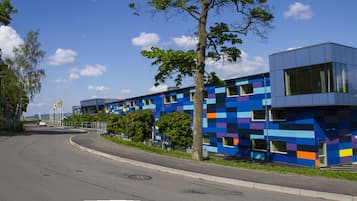 En modern byggnad med en färgstark, geometrisk fasad, en svängd väg och en klar himmel.