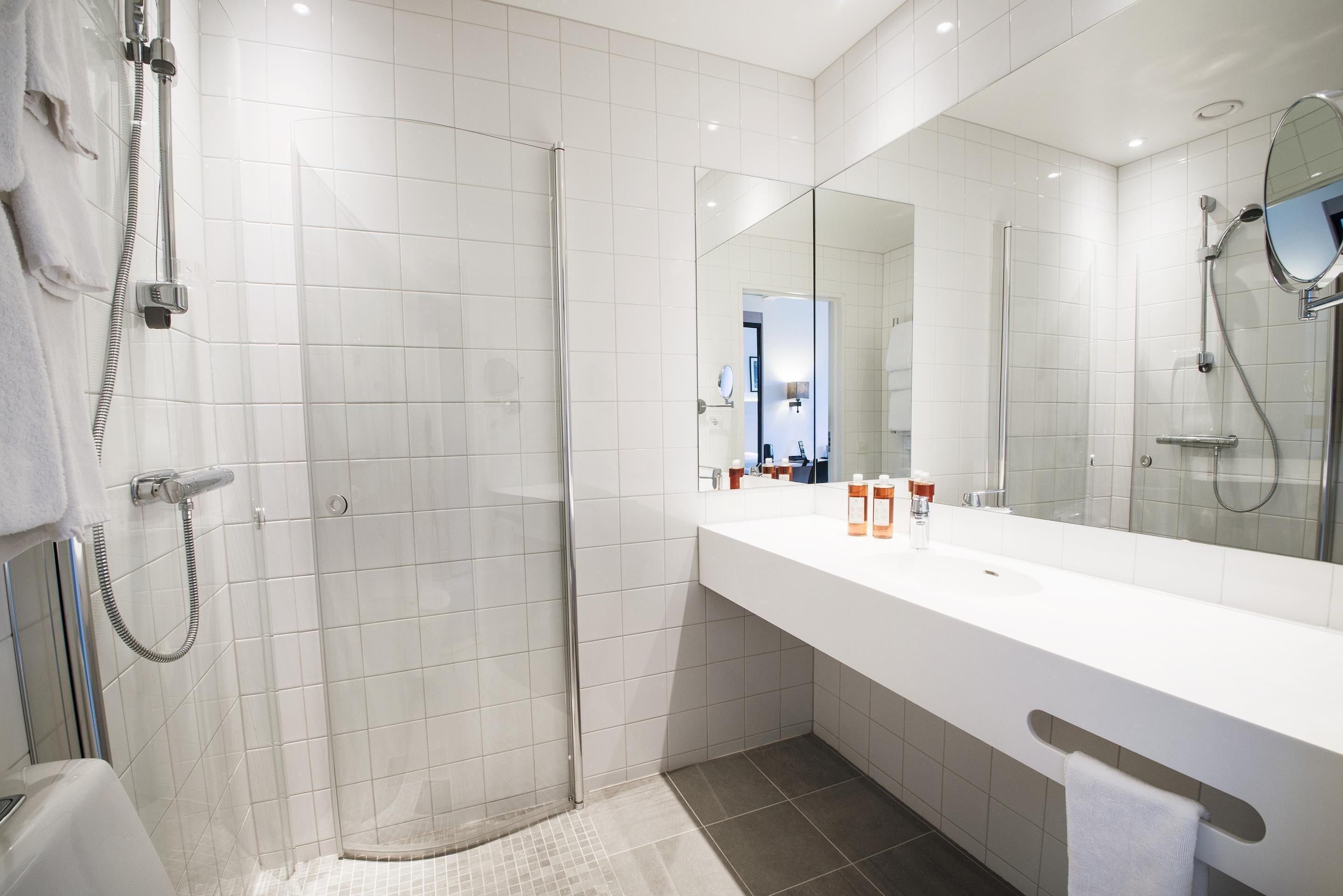 Een moderne badkamer met een douchecabine van glas, een wit wastafelmeubel en een grote spiegel.