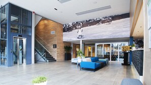 Un hall d’entrée spacieux au design moderne, comprenant un grand espace salon, un escalier et une grande fresque murale.