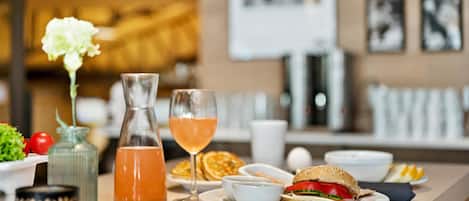 A breakfast setting with a sandwich, a glass of orange juice, and a bottle of water on a table.