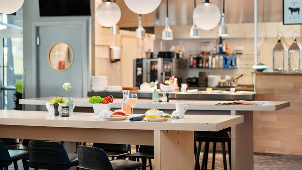 Une cuisine moderne dotée d’un îlot central, de luminaires suspendus et d’un coin repas avec des chaises.