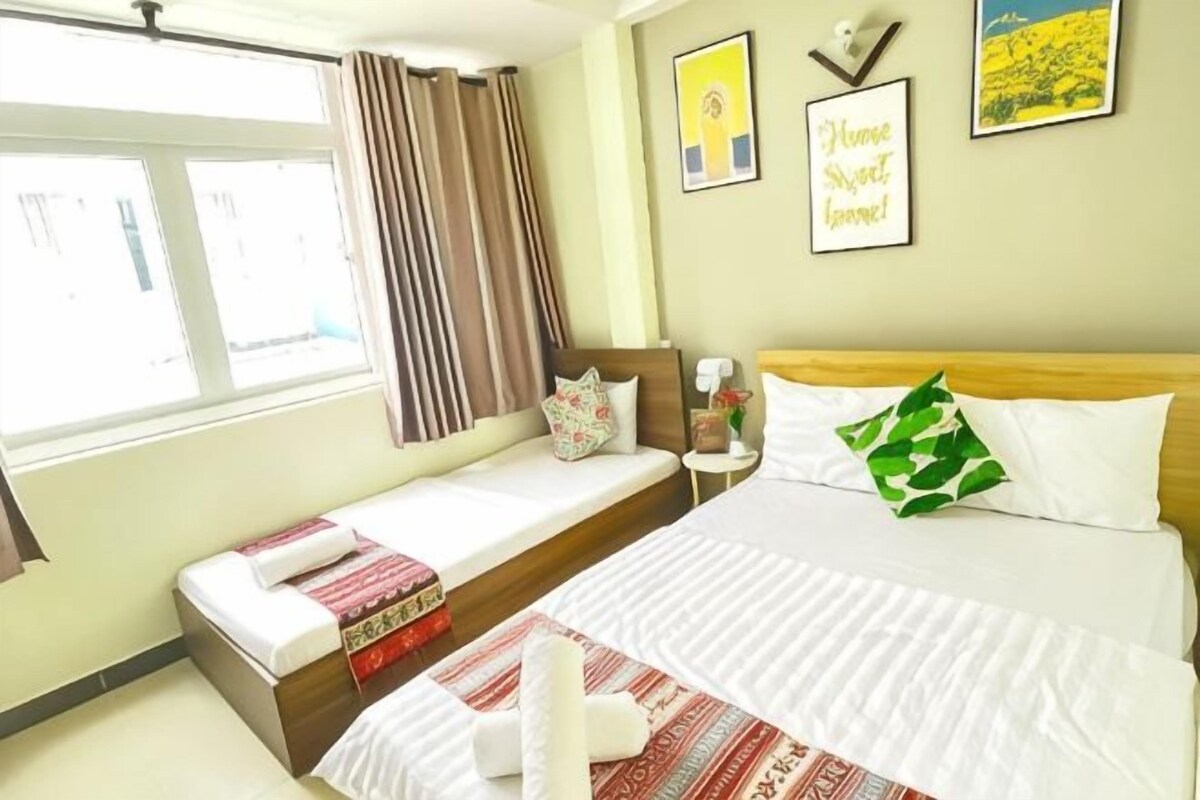 Una habitación de hotel con cama, mesita de noche, ventana con cortinas y decoración en la pared.