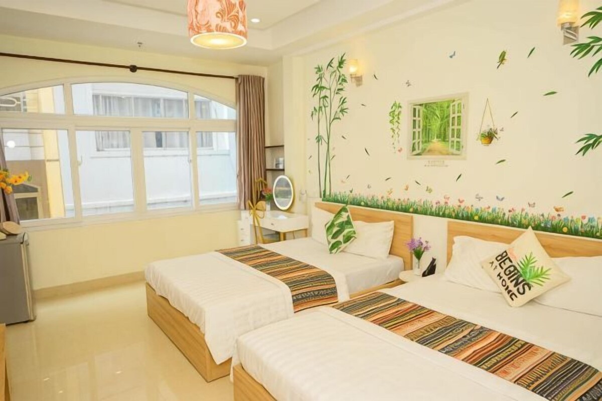 Habitación de hotel con dos camas, un escritorio, una silla, una ventana y decoración en la pared.