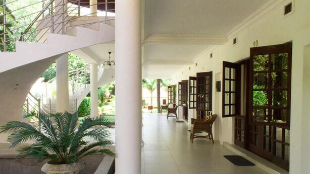 A corridor with a staircase, columns, and doors leading to rooms. - Motsamai Lodge (Bulawayo)