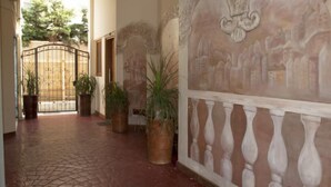 A corridor with tiled flooring, potted plants, and a decorative wall with a relief sculpture. - Sunrise Studios (Limassol)