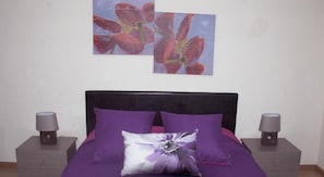 A bedroom with a bed, two nightstands, and two wall-mounted lamps.